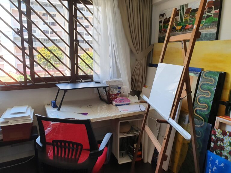 Danielle Art Original Acrylic and Oil Paintings Art studio space with desk, easel, and paintings by the window.