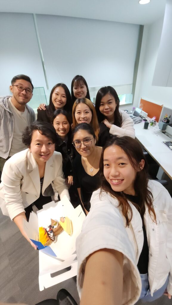 Danielle Art Original Acrylic and Oil Paintings Group of smiling colleagues celebrating with cake in an office.