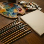Danielle Art Original Acrylic and Oil Paintings Painting supplies: canvas, palette with paints, paint tubes, and paintbrushes on a wooden table.