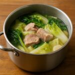 Danielle Art Original Acrylic and Oil Paintings Hearty pork and cabbage soup in a metal pot, a comforting home-cooked lunch.