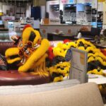 Danielle Art Original Acrylic and Oil Paintings Lion dance costume on a red leather couch in a furniture store. The sign says "Kenton".