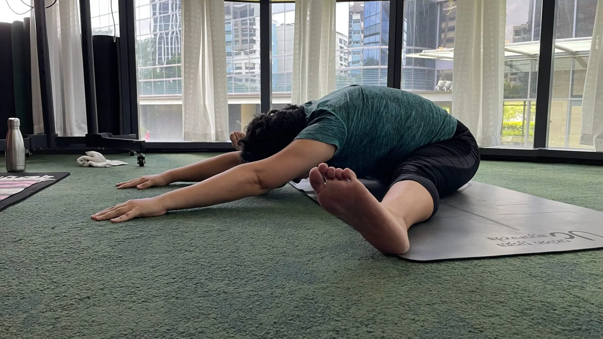 Person stretching legs in yoga pose on mat indoors.