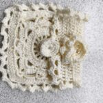 Danielle Art Original Acrylic and Oil Paintings Cream crochet doily with a circular flower embellishment on a textured surface.