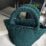 Danielle Art Original Acrylic and Oil Paintings Teal crochet potpourri pouch with handles on a countertop.