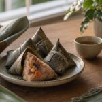 Traditional bak chang rice dumplings wrapped in bamboo leaves on a warm home table
